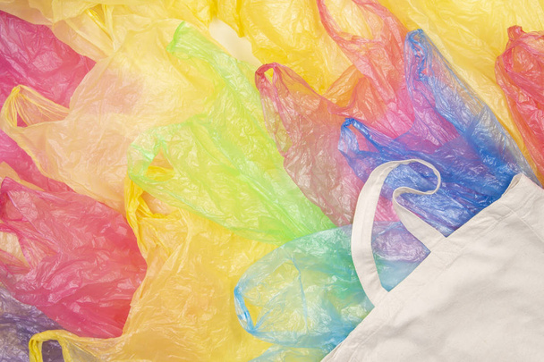 Mnoho různobarevné plastové sáčky s jedním pozadím přírodní opakovaně použitelné nákupní taška eco. Nula odpadů, eco přátelské, udržitelnost životního stylu, žádné plastové koncepce - Fotografie, Obrázek