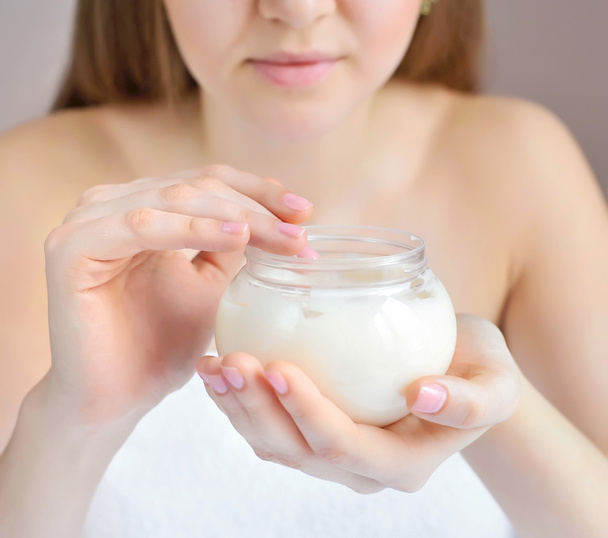 Beautiful hands of young woman are with the jar of cream. Focus is on a hand - 写真・画像