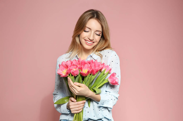 Portrait of beautiful smiling girl with spring tulips on pink background. International Women's Day - Фото, изображение