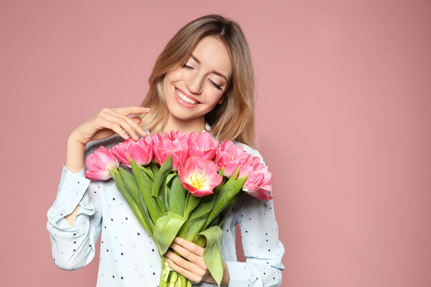 Portrait of beautiful smiling girl with spring tulips on pink background. International Women's Day - Foto, Bild