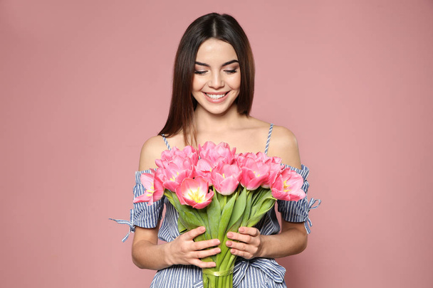 Portret van mooi lachende meisje met lente tulpen op roze achtergrond. Internationale Vrouwendag - Foto, afbeelding