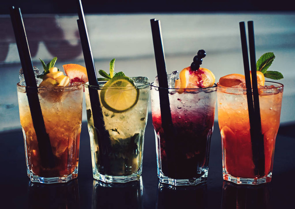 A full measure of bars. Cocktail drinks served in glasses with straws. Iced drinks in cocktail glasses. Alcoholic mixed drinks with ice. Juicy beverages with alcohol on counter. Alcohol addiction - Φωτογραφία, εικόνα