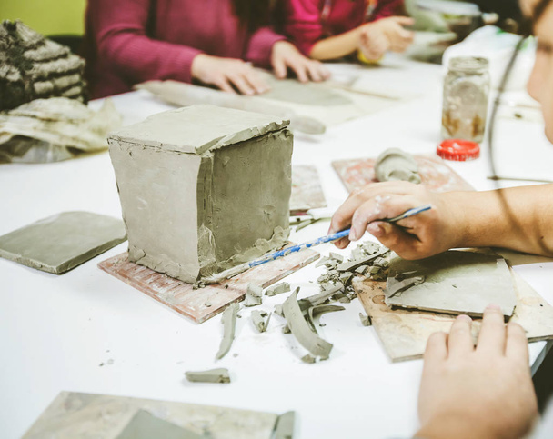Petites mains d'artiste travaillant avec de l'argile à l'atelier de poterie
 - Photo, image