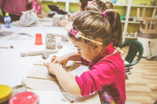 Çocuk çömlek atölyesi, küçük kız kille çalışıyor, yaratıcı öğrenme. - Fotoğraf, Görsel