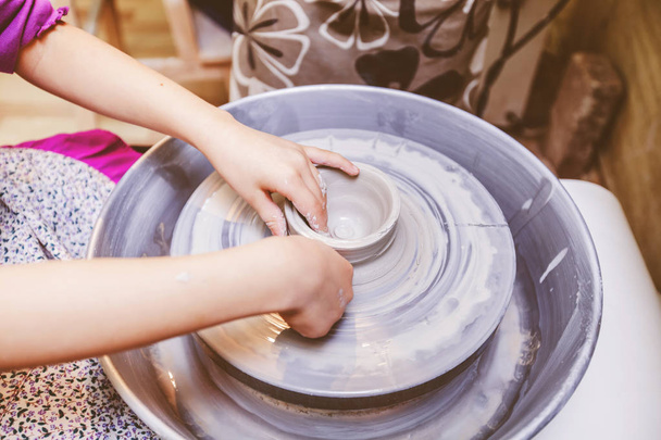 若い陶芸家の手は、工房で陶芸ホイール上の粘土でセラミック花瓶を形成する - 写真・画像