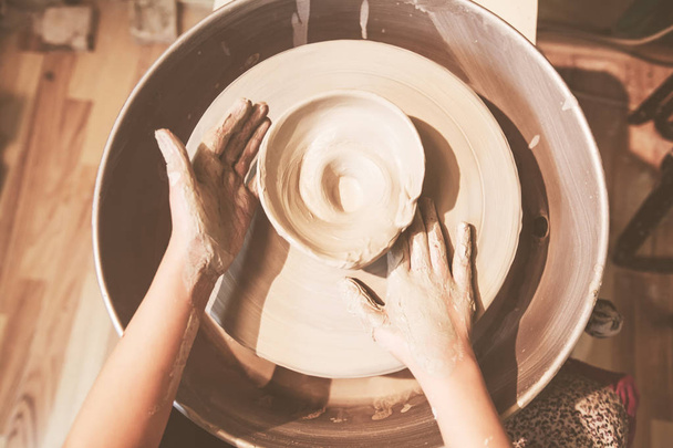 Jeunes mains de potier formant un vase en céramique avec de l'argile sur une roue de poterie à l'atelier
 - Photo, image