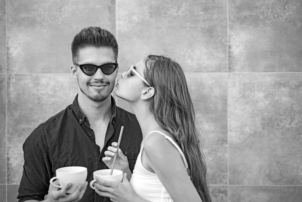 What else is there to do than kiss. Girlfriend and boyfriend have espresso drink together. Couple of woman and man with coffee cups. Couple in love drink coffee outdoor. Enjoying the best coffee date - Foto, imagen
