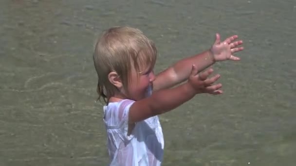 Beautiful little girl walks along the seashore. Little girl in a white dress on the coast. Slow motion. - Footage, Video