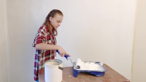Teen dívka malba vnitřní stěny v bytě pomocí válečkem. Dítě, sám dělá opravy v jejím pokoji - aktivně barvy stěny s bílou barvou. Renovaci domů nebo vymalování koncepce. - Záběry, video