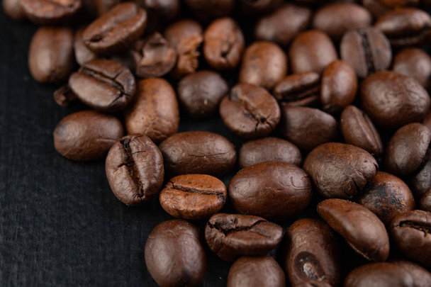 Tasty roasted coffee beans on the table. Black coffee beans stra - Фото, зображення