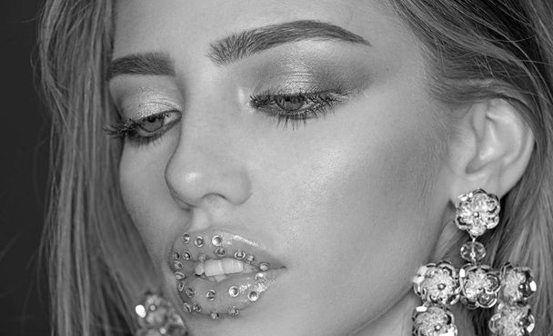 Sexy woman with glitter gem on lips. Fashion model with trendy look. Beauty on party. My favorite earrings. Girl with sexy lips makeup. Glamour jewelry of luxury big earrings. Success and riches - Φωτογραφία, εικόνα