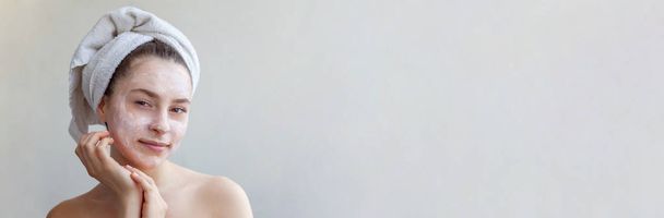 Portret van de schoonheid van de vrouw in de handdoek op kop met witte voedende masker of crème op het gezicht, witte achtergrond geïsoleerd. Huidverzorging reinigende eco organische cosmetische spa relax concept Banner - Foto, afbeelding