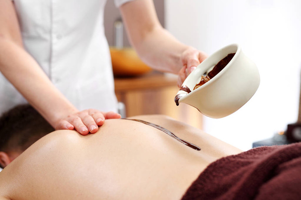 Chocolate back massage. A man on a massage treatment in a wellness salon. - Fotografie, Obrázek