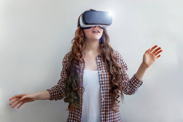 Sorridi giovane donna indossando occhiali VR realtà virtuale casco auricolare su sfondo bianco. Smartphone utilizzando con occhiali di realtà virtuale. Tecnologia, simulazione, hi-tech, concetto di videogioco - Foto, immagini