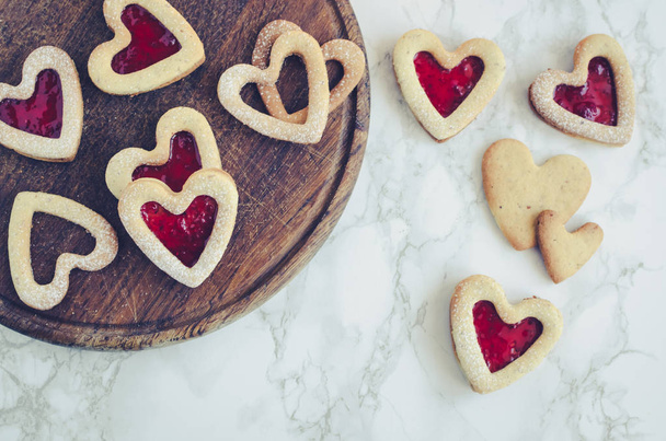 V srdci se ve tvaru koláčků Linzer s marmeládou pro Valentýnský den na mramorovém pozadí. Vynikající domácí pečivo. Pečení s milostné koncepcí. Pohled shora. - Fotografie, Obrázek