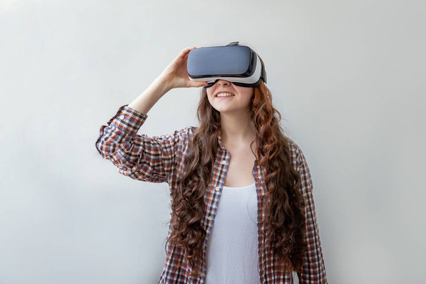 Lach jonge vrouw dragen met behulp van virtual reality VR bril helm headset op witte achtergrond. Smartphone met virtual reality bril. Technologie, simulatie, hightech, videogame concept - Foto, afbeelding