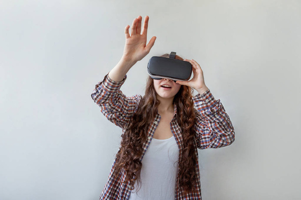 Úsměv mladá žena nosí pomocí virtuální reality VR brýle helma headset na bílém pozadí. Smartphone s brýlemi pro virtuální realitu. Technologie, simulace, hi-tech, videoherní koncept - Fotografie, Obrázek