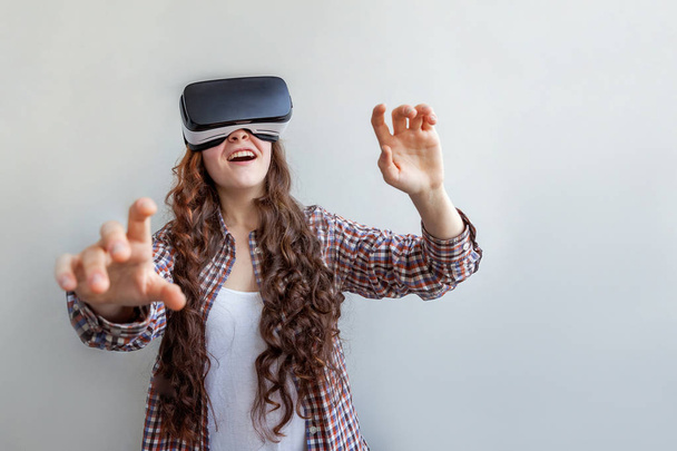 Sonríe mujer joven usando realidad virtual gafas VR casco auriculares sobre fondo blanco. Smartphone con gafas de realidad virtual. Tecnología, simulación, alta tecnología, concepto de videojuego - Foto, Imagen