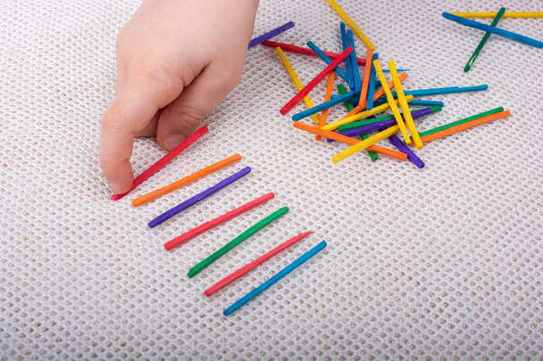 Bambino che gioca con bastoncini di legno colorati per la creatività su sfondo bianco - Foto, immagini