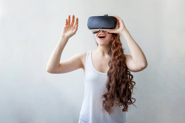 Lach jonge vrouw dragen met behulp van virtual reality VR bril helm headset op witte achtergrond. Smartphone met virtual reality bril. Technologie, simulatie, hightech, videogame concept - Foto, afbeelding