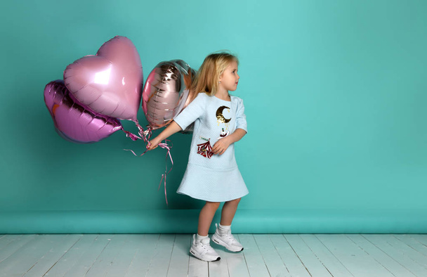 little girl has fun with a bunch of pink air balloons in the shape of her heart. - Valokuva, kuva