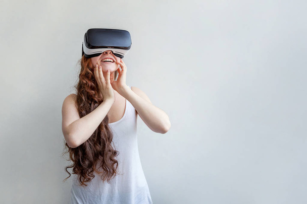 Smile young woman wearing using virtual reality VR glasses helmet headset on white background. Smartphone using with virtual reality goggles. Technology, simulation, hi-tech, videogame concept - Valokuva, kuva