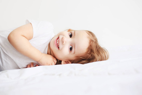 little girl smiling lying on a bed - 写真・画像