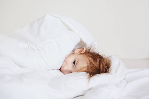 little girl sleeping under a white blanket - Valokuva, kuva