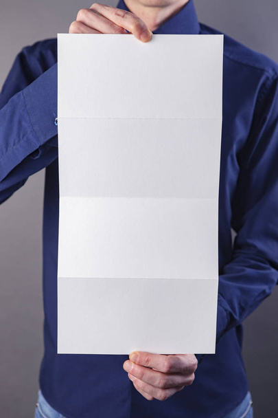 A man holding white booklet - Fotó, kép