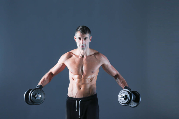 Handsome muscular man working out with dumbbells. Personal fitness instructor. Personal training. - Foto, imagen