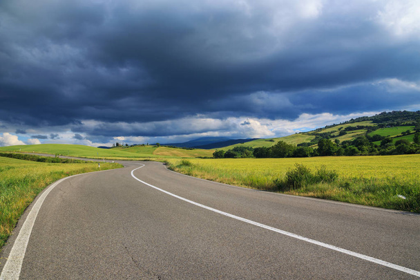 Kurvikas asfalttitie Toscanassa ja dramaattiset pilvet taivaalla. Italia
 - Valokuva, kuva