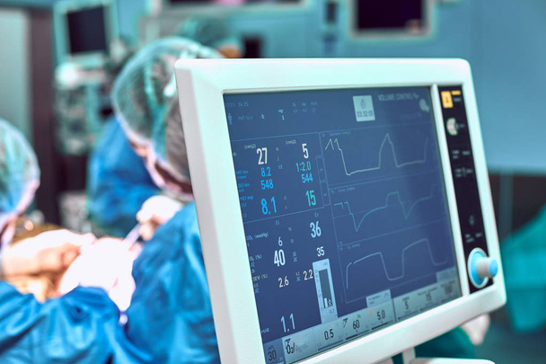 Überwachung der Patienten Lebenszeichen im Operationssaal im Fokus. auf Backgdound blauer Chirurgie der Kinnverkleinerung Augmentation Doppelkinnentfernung - Foto, Bild