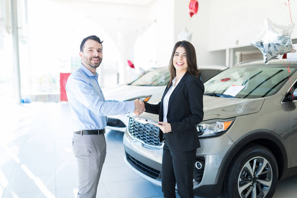 Gerente de ventas de confianza haciendo que el cliente se sienta cómodo antes de comprar un coche en la sala de exposición
 - Foto, imagen