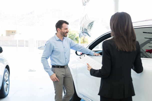 Smiling mid adult customer planning to buy luxury car from dealership - Photo, Image