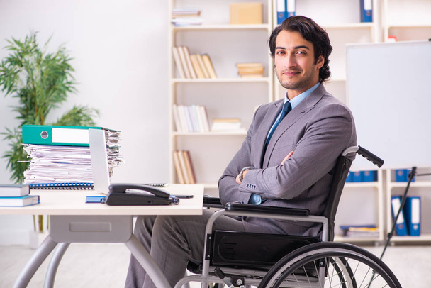 Young handsome employee in wheelchair at the office - Foto, Imagem