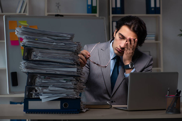 Joven empleado masculino trabajando hasta tarde en la oficina
 - Foto, imagen
