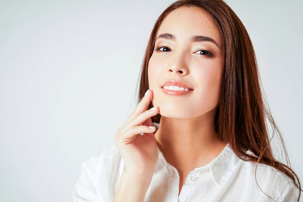 Краса портрет усміхненої чуттєвої азіатської молодої жінки з чистою свіжою шкірою в білій сорочці ізольовані
 - Фото, зображення