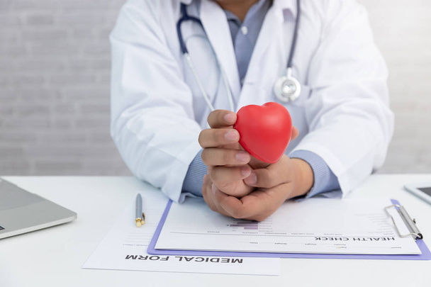 Sağlık ve tıp kavramı, klinikte kırmızı kalp topu tutan doktor. - Fotoğraf, Görsel