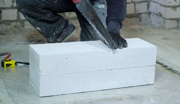 construction worker in gloves sawing aerated concrete block - Photo, Image