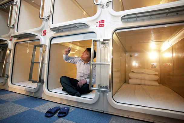 Un Chinois vérifie le rideau de sa chambre à l'hôtel capsule de Shanghai, en Chine, le 9 janvier 2011
 - Photo, image