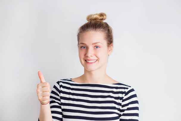 Successful young beautiful blonde woman smiling and showing thumbs up on white background with copy space. Positive emotions, facial expression, gestures concept - Foto, Bild