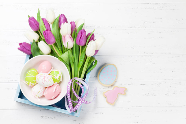 Easter greeting card with tulip flowers bouquet and easter eggs. Top view over white wooden table with space for your greetings - Fotoğraf, Görsel