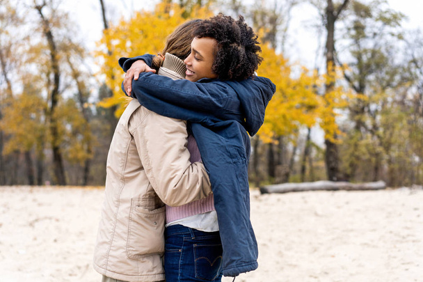 Ερωτευμένο ζευγάρι είναι το περπάτημα στο πάρκο φθινόπωρο. Afroamerican κορίτσι με ένα Ευρωπαϊκό. - Φωτογραφία, εικόνα