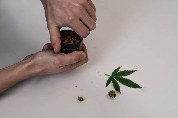 The man rolling medical marijuana joint. Marijuana buds, weed, leaf and gringer on white background. Cannabis - Fotoğraf, Görsel
