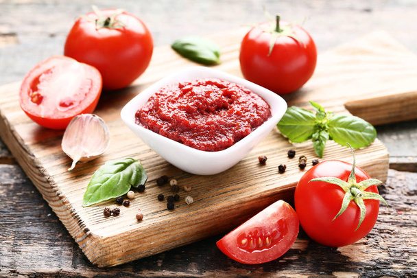 Ketchup in bowl with basil leafs and pepper on wooden table - Φωτογραφία, εικόνα