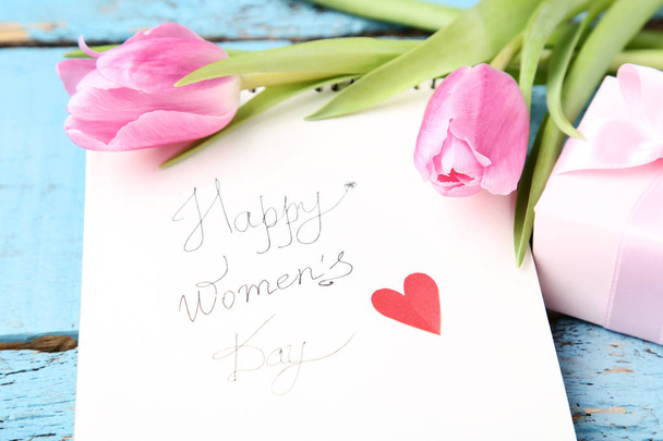 Text Happy Women's Day with pink tulip flowers and gift box on wooden table - 写真・画像