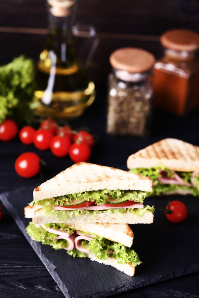 ハム、チーズ、黒の木製テーブルの上の野菜のサンドイッチ - 写真・画像