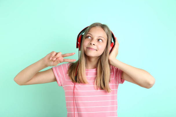 Beautiful young girl with headphones on mint background - Fotoğraf, Görsel
