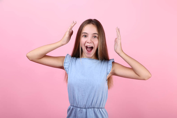 Young screaming girl in blue dress on pink background - Fotó, kép