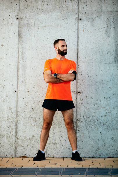 Male runner standing with crossed arms in sportswear outdoors. Healthy lifestyle concept. - Valokuva, kuva